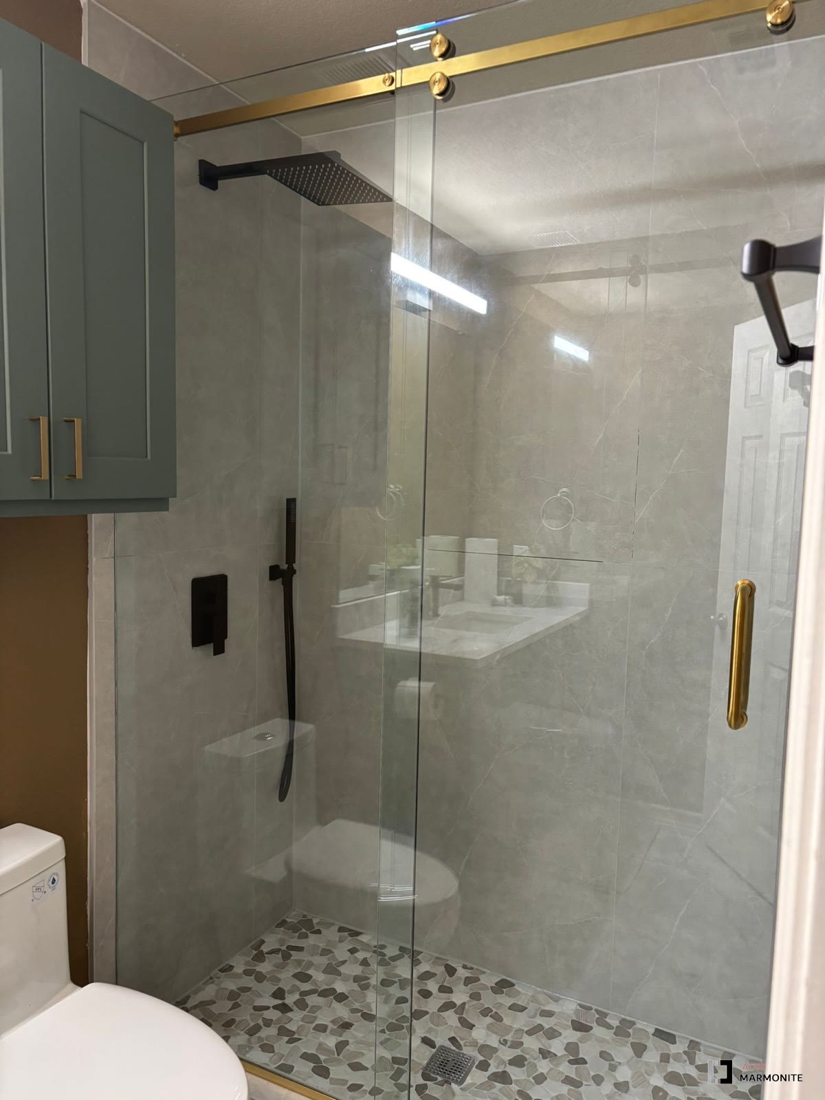 Frameless glass shower with marble tile and gold hardware